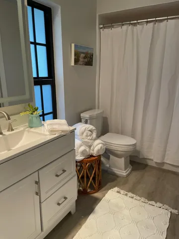 a bathroom with a sink a toilet a mirror and shower curtain
