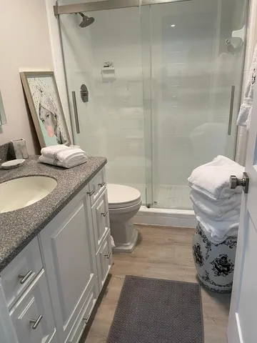 a bathroom with a granite countertop sink a toilet a mirror and shower