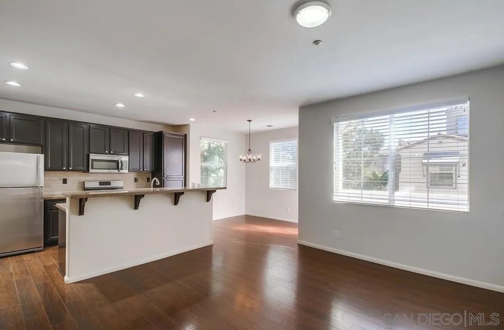 1298 Fools Gold Way, Unit 4 Chula Vista, CA 91913 - Photo 6 of 38 a view of a kitchen with kitchen island a sink wooden floor and a refrigerator
