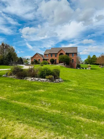 a view of a big house with a big yard plants and large trees