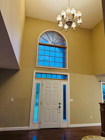 a view of a hallway with wooden floor and chandelier