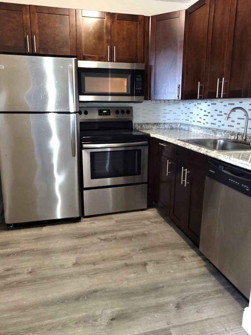 2711 Vandiver Drive, Unit 307 West Palm Beach, FL 33409 - Photo 2 of 15 a kitchen with kitchen island granite countertop a refrigerator stove and microwave