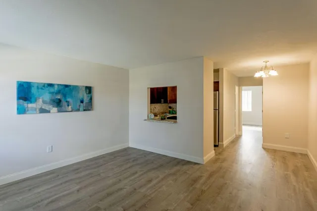 a view of a hallway with wooden floor and chair in a room