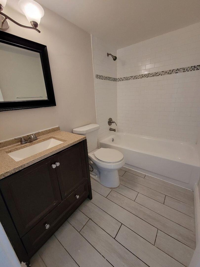 2711 Vandiver Drive, Unit 307 West Palm Beach, FL 33409 - Photo 5 of 15 a bath room with a toilet a sink and a mirror