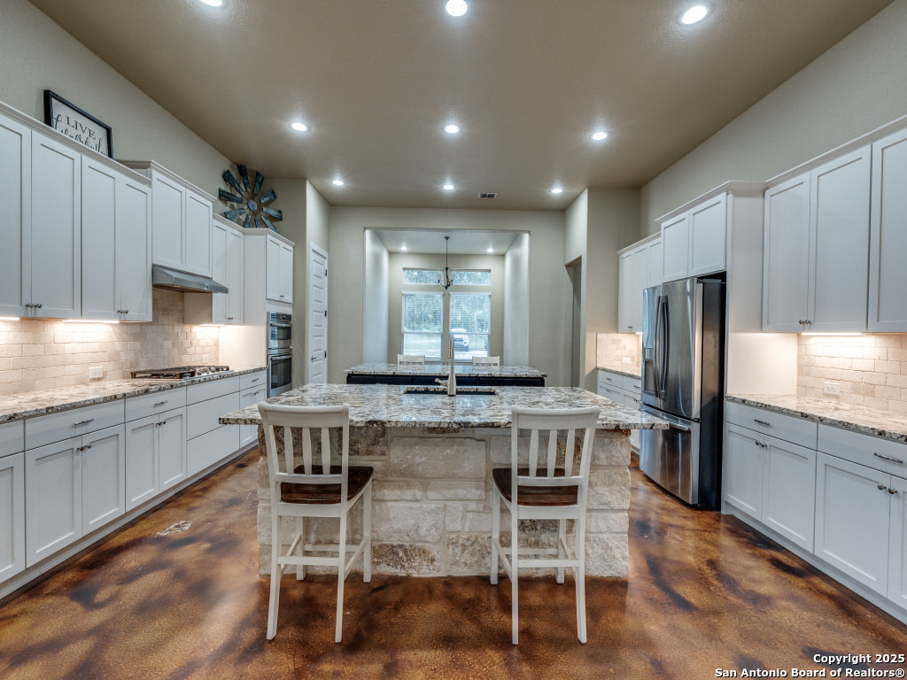 629 Windmill Ranch Road Spring Branch, TX 78070 - Photo 14 of 34 a kitchen with kitchen island granite countertop wooden cabinets and stainless steel appliances