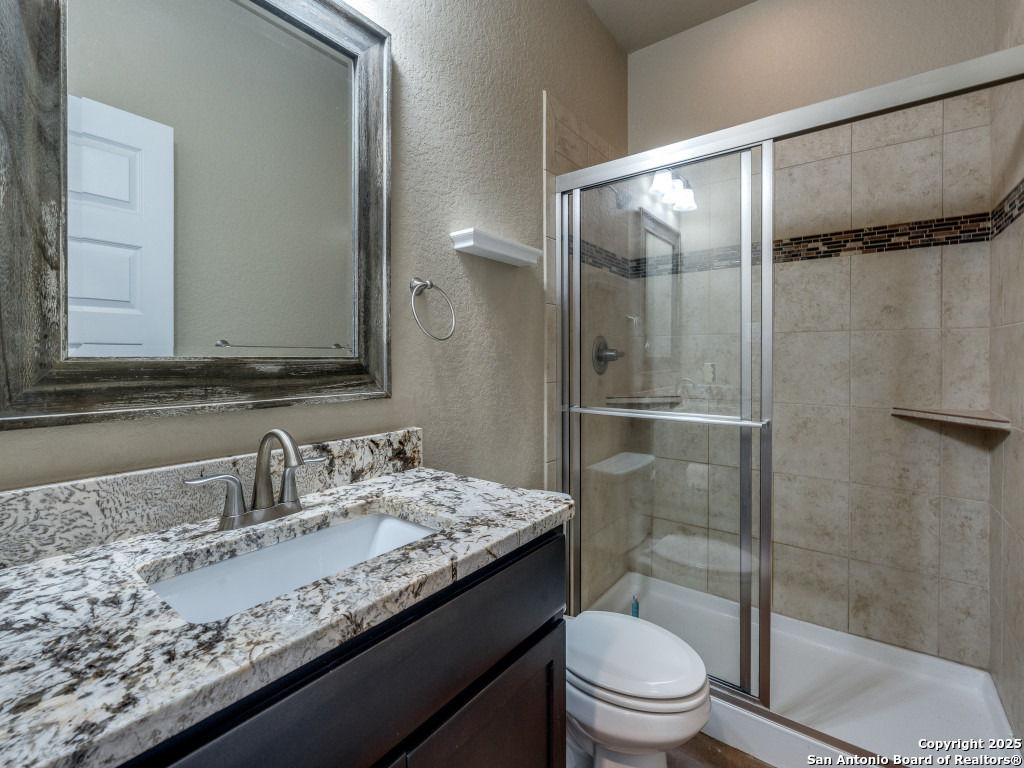 629 Windmill Ranch Road Spring Branch, TX 78070 - Photo 25 of 34 a bathroom with a granite countertop sink toilet and shower