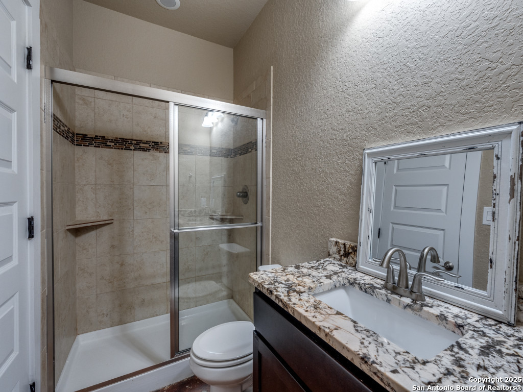 629 Windmill Ranch Road Spring Branch, TX 78070 - Photo 28 of 34 a bathroom with a granite countertop sink toilet and shower