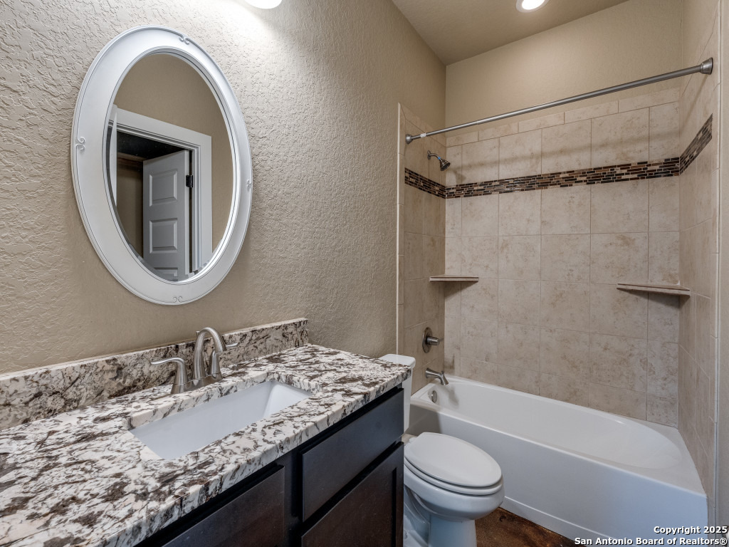 629 Windmill Ranch Road Spring Branch, TX 78070 - Photo 30 of 34 a bathroom with a granite countertop sink a toilet and a mirror