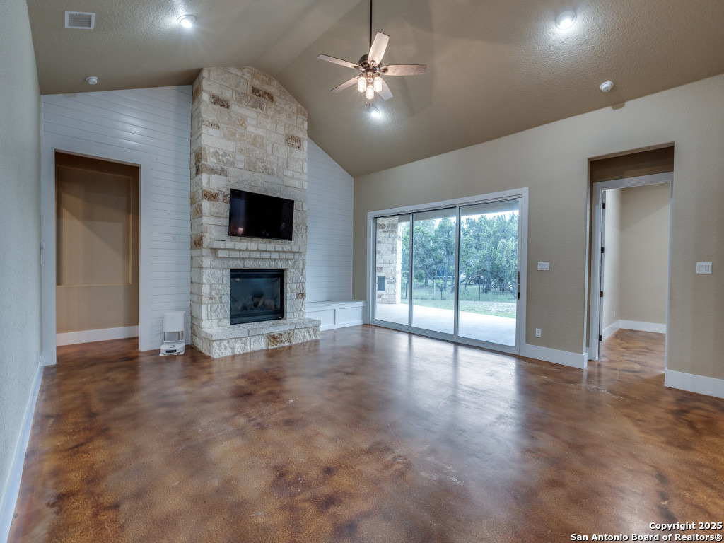 629 Windmill Ranch Road Spring Branch, TX 78070 - Photo 6 of 34 an empty room with windows fireplace and fan