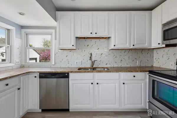 a kitchen with granite countertop white cabinets and stainless steel appliances