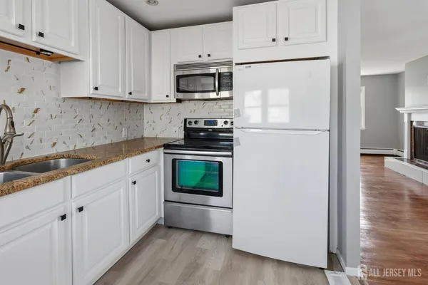 a kitchen with cabinets stainless steel appliances a sink and wooden floor