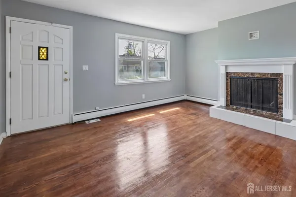 an empty room with wooden floor fireplace and windows