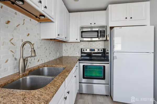 a kitchen with white cabinets a sink and stainless steel appliances