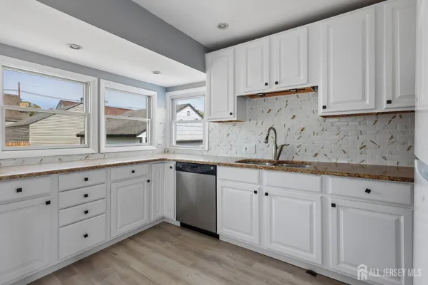 a kitchen with granite countertop white cabinets and sink