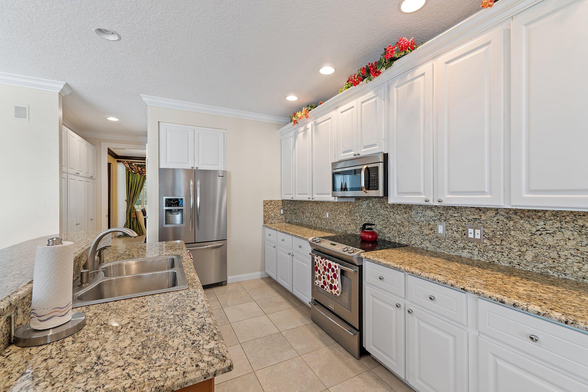 115 Castries Drive Jupiter, FL 33458 - Photo 8 of 60 a kitchen with stainless steel appliances granite countertop a sink stove and refrigerator