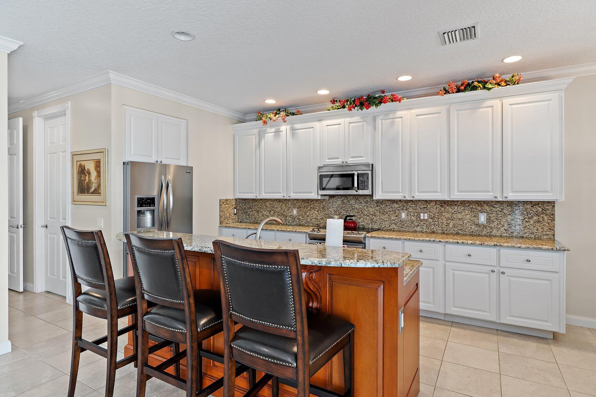 115 Castries Drive Jupiter, FL 33458 - Photo 9 of 60 a kitchen with stainless steel appliances a white table chairs and a refrigerator