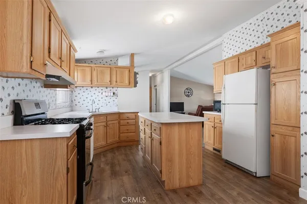 a kitchen with a refrigerator a stove a sink dishwasher and wooden cabinets with wooden floor
