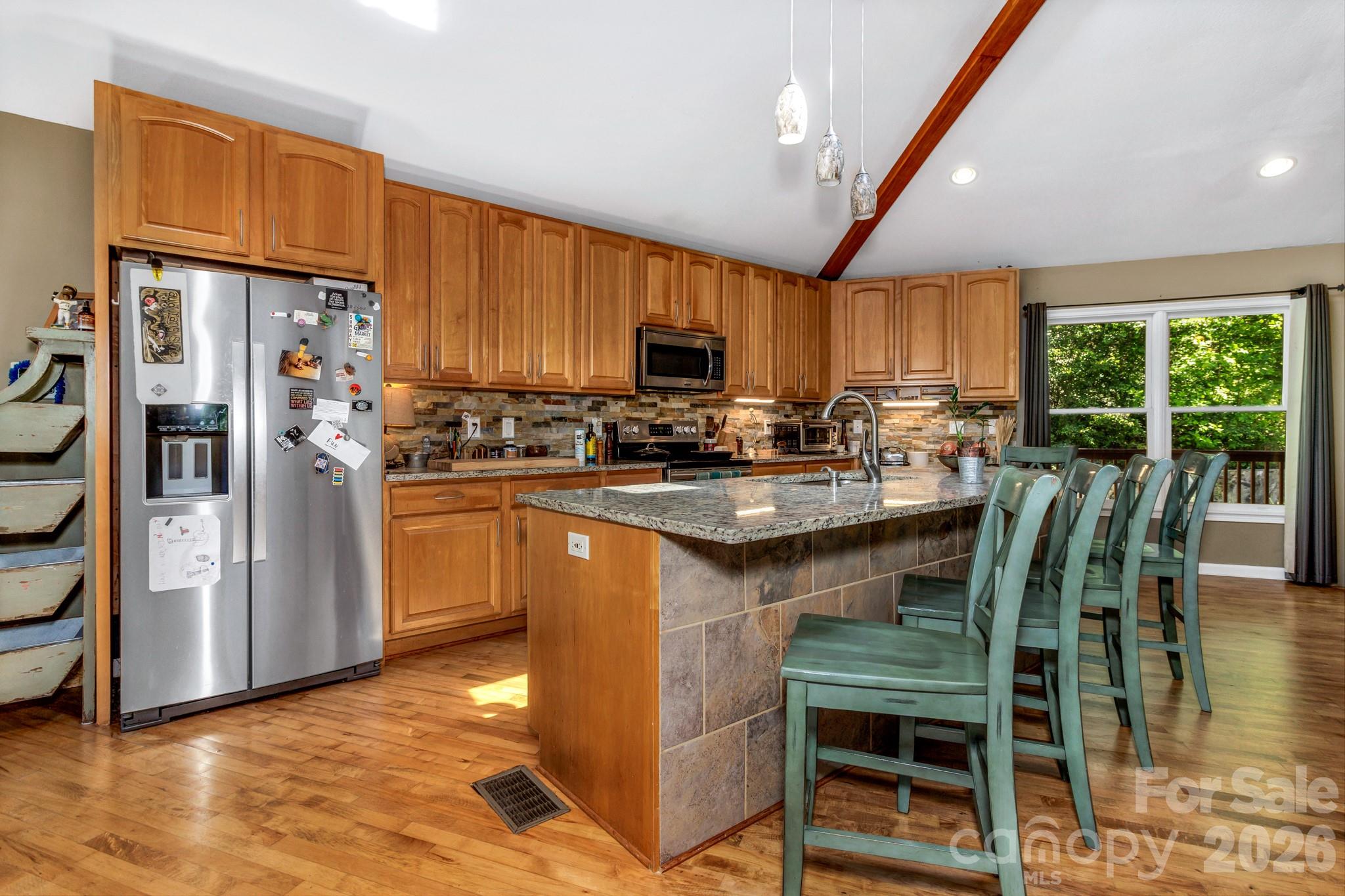 125 Winding Ridge Road Asheville, NC 28803 - Photo 12 of 48 a kitchen with stainless steel appliances granite countertop a stove a refrigerator a kitchen island a stove a dining table and chairs with wooden floor