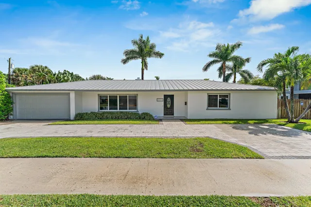 a front view of a house with a garden and palm tree