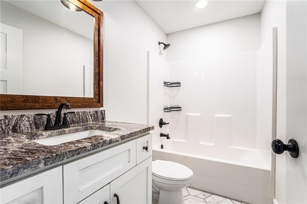 1550 Knox Chapel Road Social Circle, GA 30025 - Photo 29 of 35 a bathroom with a granite countertop sink toilet mirror and shower