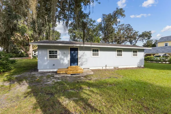 a view of a house with a yard and a tree