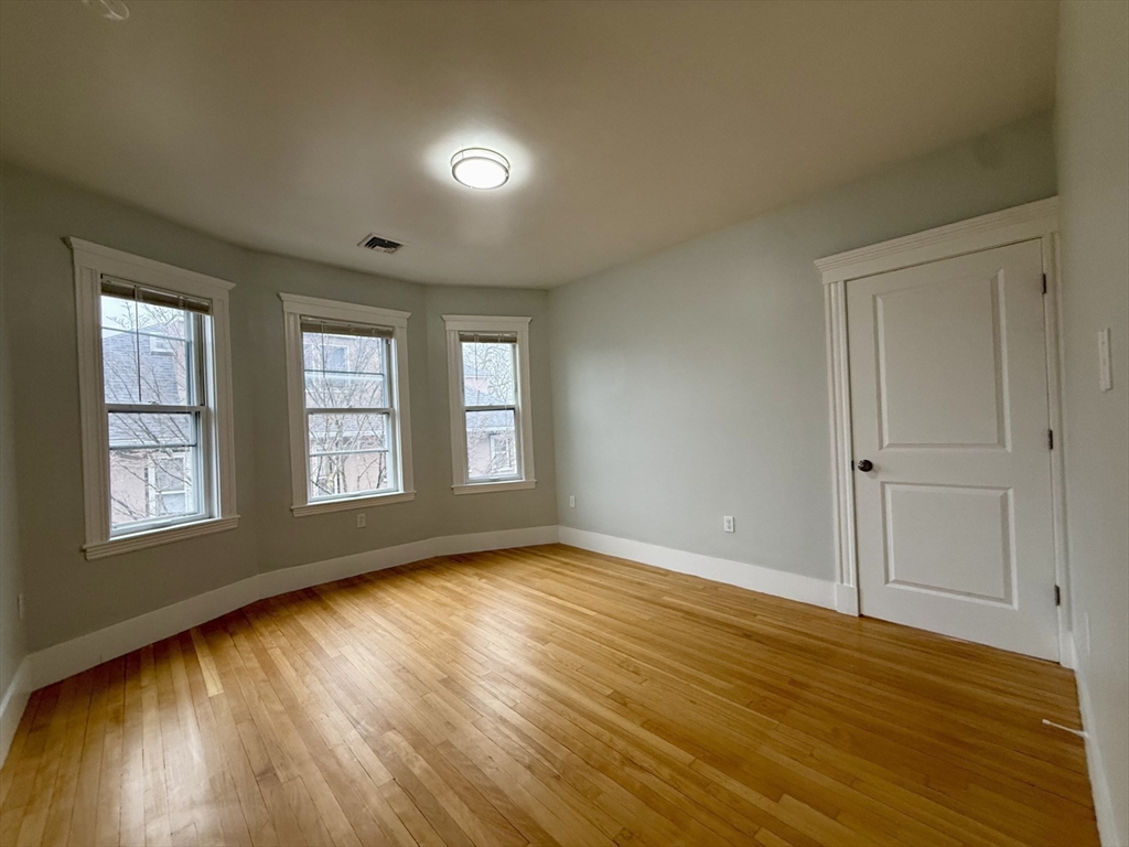 174 Maplewood Street, Unit 174 Watertown, MA 02472 - Photo 16 of 30 a view of an empty room with wooden floor and window