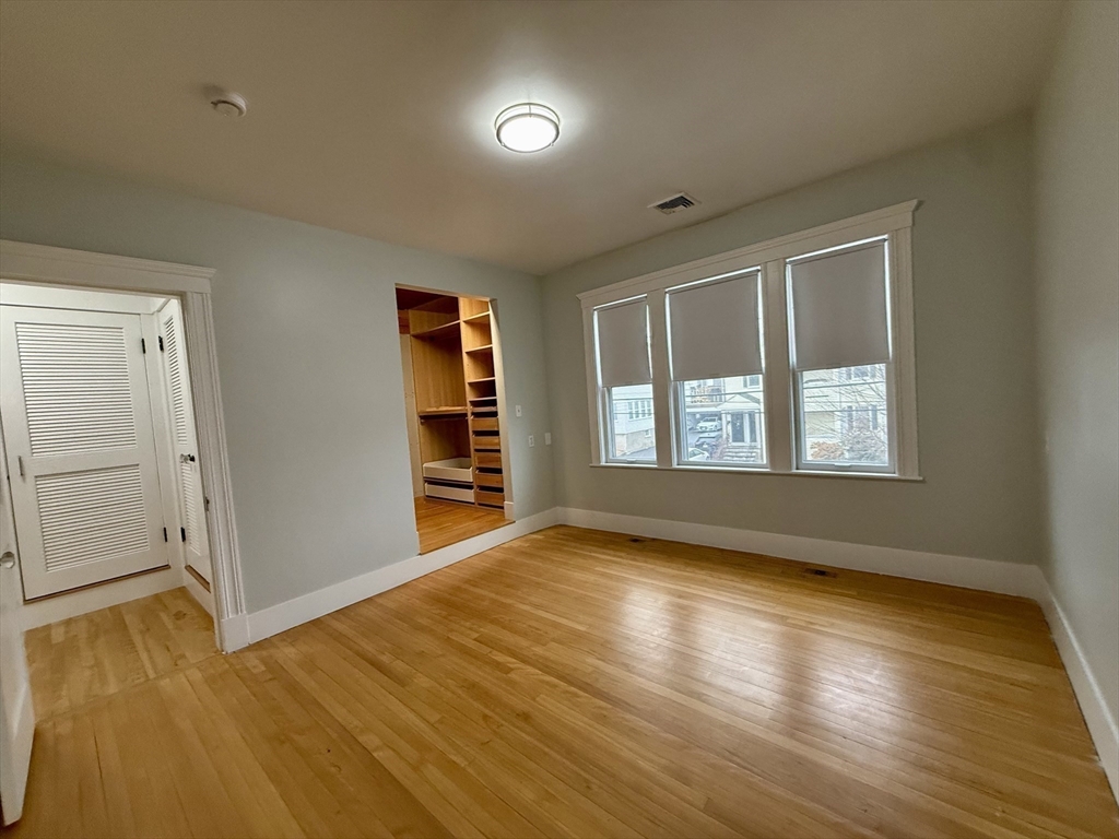 174 Maplewood Street, Unit 174 Watertown, MA 02472 - Photo 19 of 30 an empty room with wooden floor and windows