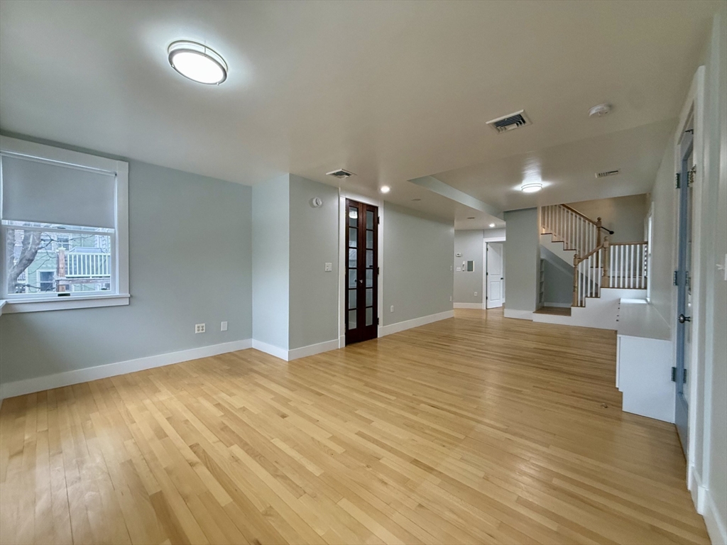 174 Maplewood Street, Unit 174 Watertown, MA 02472 - Photo 4 of 30 a view of an empty room with wooden floor and a window