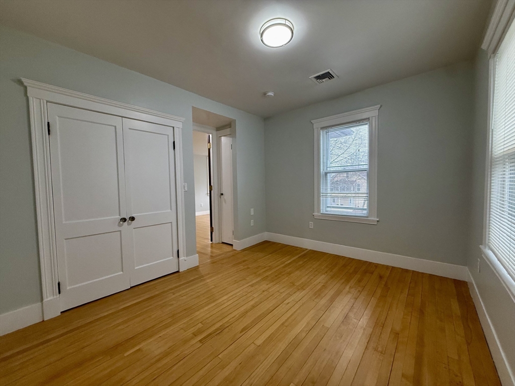 174 Maplewood Street, Unit 174 Watertown, MA 02472 - Photo 8 of 30 an empty room with wooden floor and windows