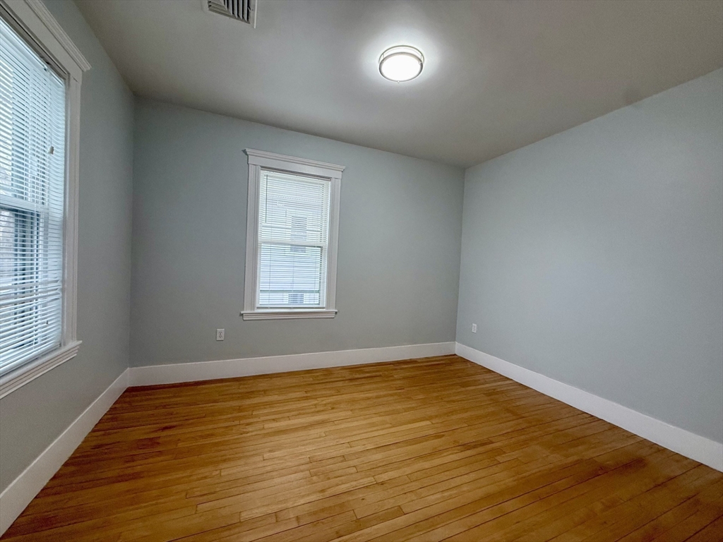 174 Maplewood Street, Unit 174 Watertown, MA 02472 - Photo 9 of 30 an empty room with wooden floor and windows