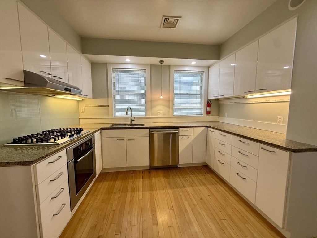 174 Maplewood Street, Unit 174 Watertown, MA 02472 - Photo 10 of 30 a kitchen with granite countertop a stove top oven sink and cabinets