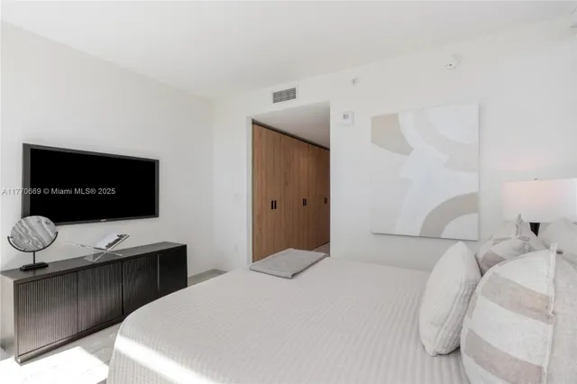 a spacious bedroom with a bed and a flat screen tv