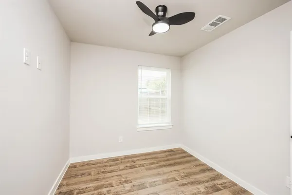 an empty room with a window and ceiling fan