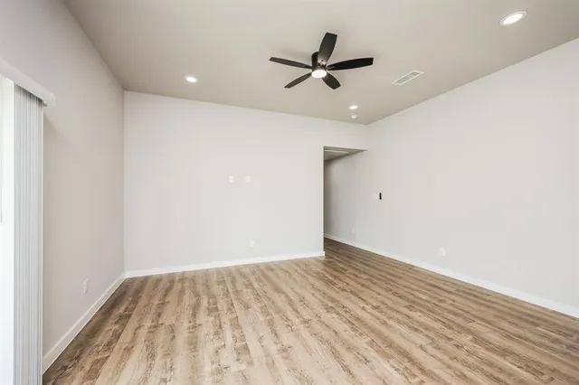 a view of a room with wooden floor and a ceiling fan