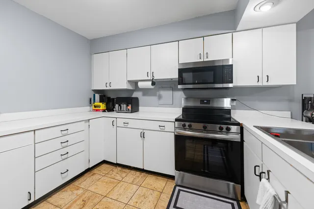 a kitchen with granite countertop white cabinets and stainless steel appliances