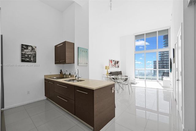 a view of a kitchen with a sink wooden cabinets and a living room view