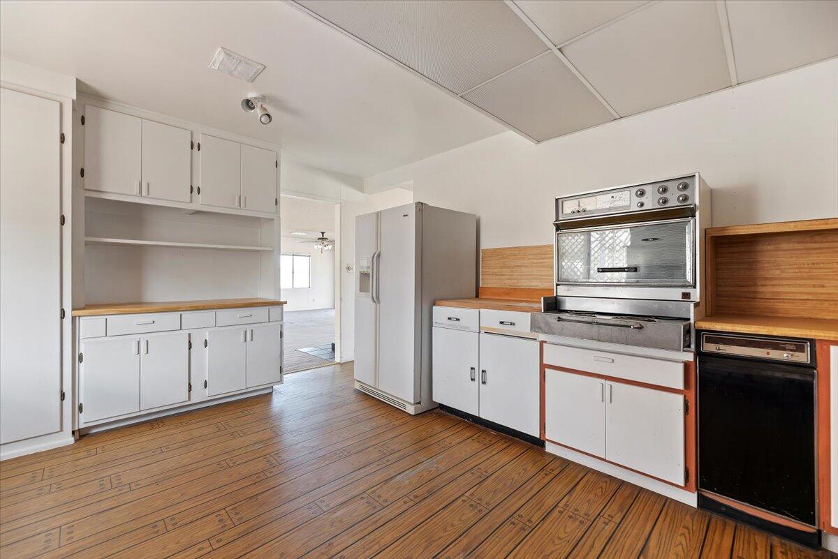 61313 El Coyote Lane Joshua Tree, CA 92252 - Photo 25 of 48 a kitchen with stainless steel appliances white cabinets and wooden floors