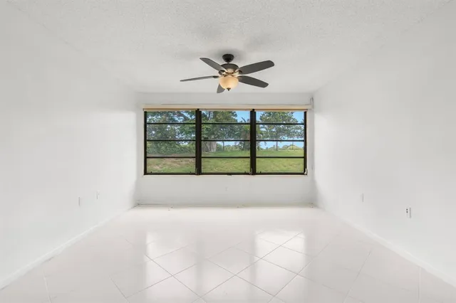 an empty room with windows and ceiling fan