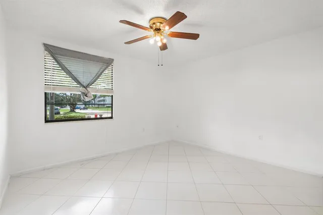 an empty room with a window and a ceiling fan