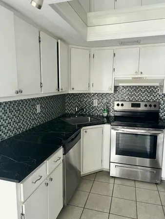 a kitchen with granite countertop white cabinets and black appliances