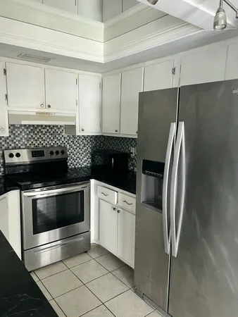 a kitchen with a refrigerator and white cabinets