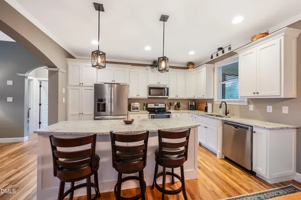 a kitchen with stainless steel appliances a table chairs refrigerator and microwave