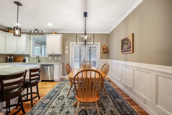 a kitchen with stainless steel appliances granite countertop a dining table chairs refrigerator and sink