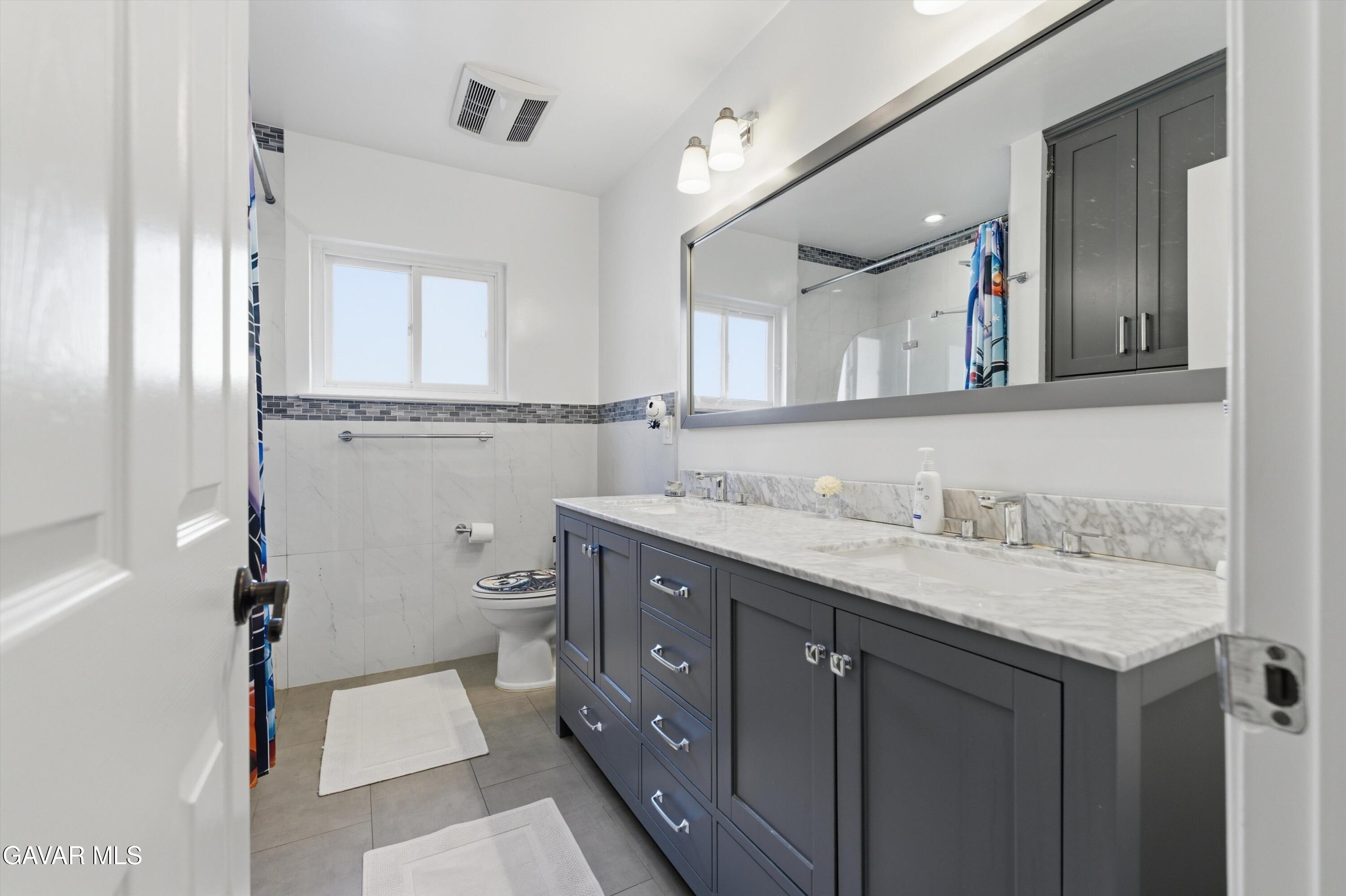 9065 Elizabeth Lake Road Leona Valley, CA 93551 - Photo 26 of 58 a bathroom with a granite countertop toilet sink and mirror