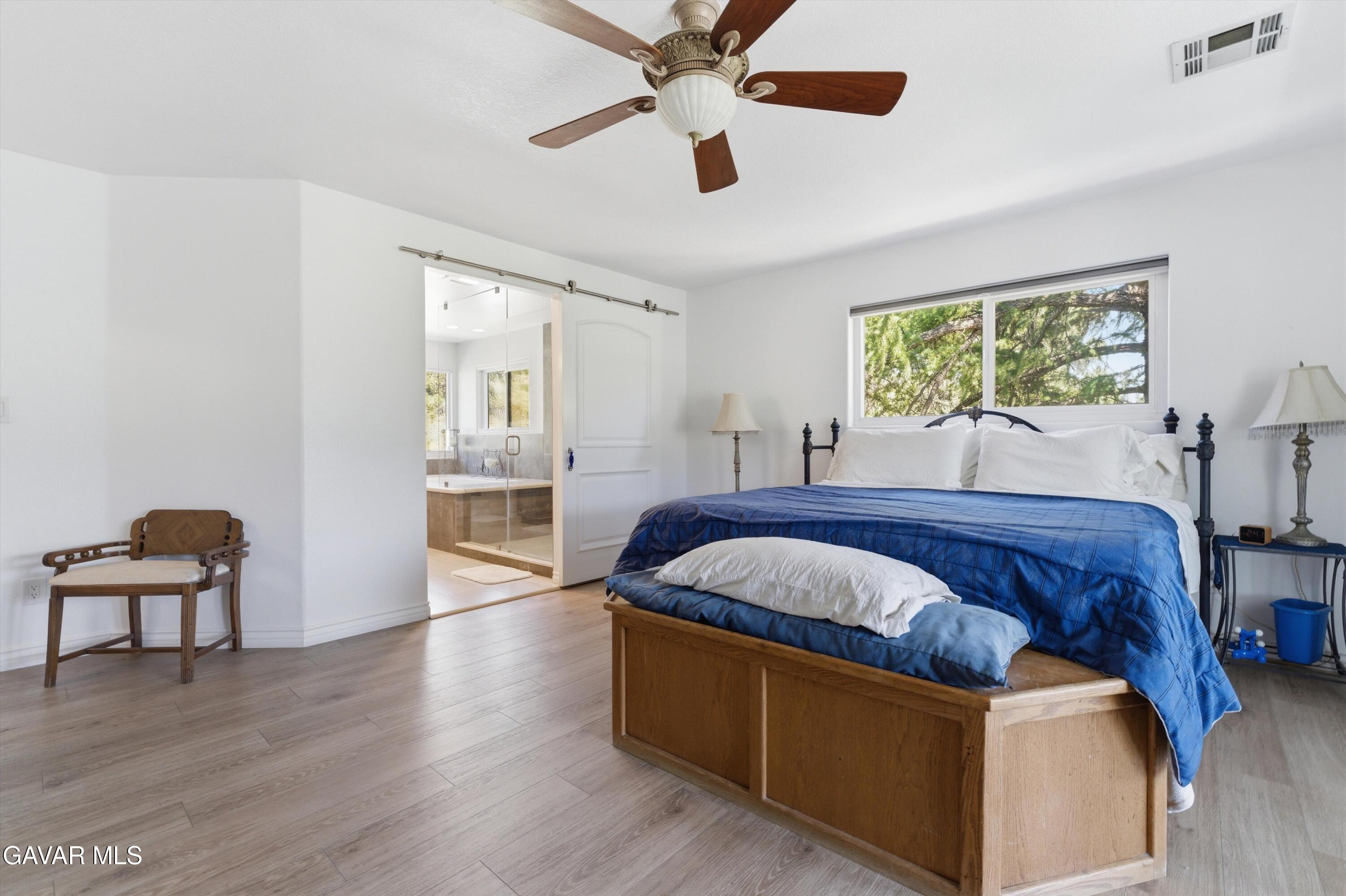 9065 Elizabeth Lake Road Leona Valley, CA 93551 - Photo 27 of 58 a spacious bedroom with a bed and wooden floor