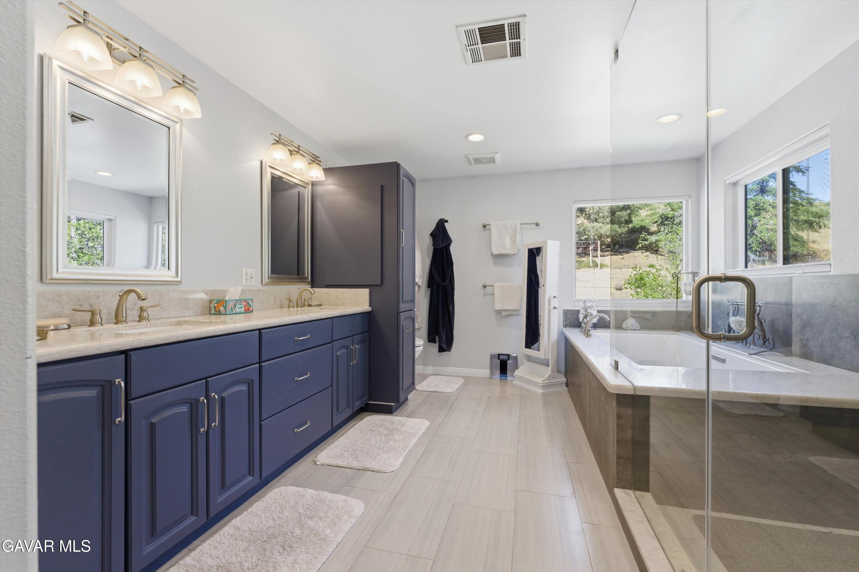 9065 Elizabeth Lake Road Leona Valley, CA 93551 - Photo 28 of 58 a spacious bathroom with a tub double sink window and mirror