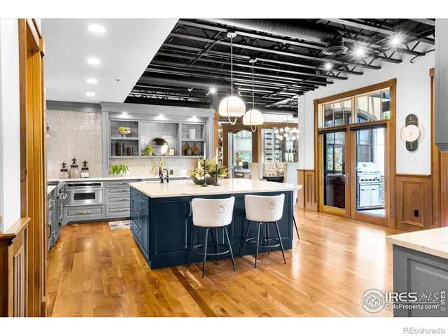 a living room with stainless steel appliances kitchen island granite countertop a large kitchen view and a wooden floors