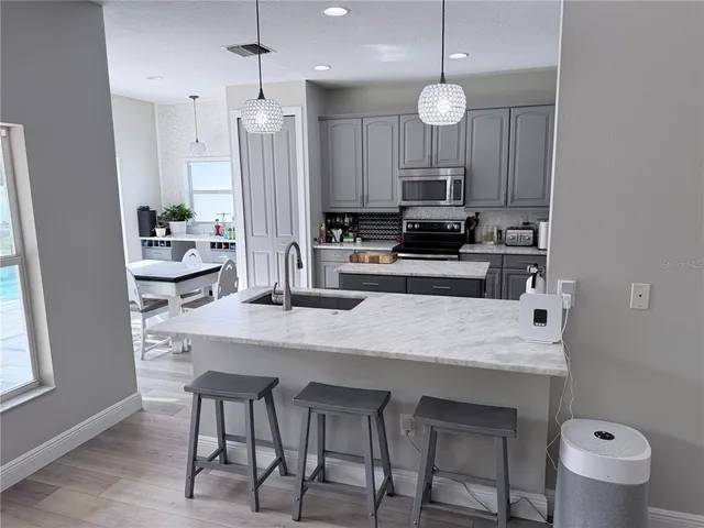 a kitchen with kitchen island a dining table chairs and a sink