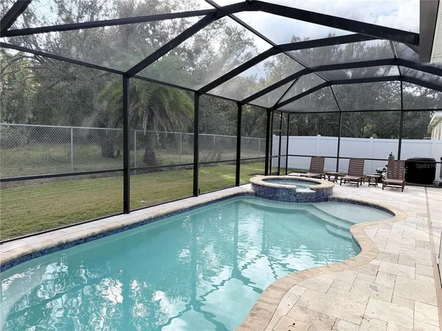 a view of a swimming pool with a patio and a yard