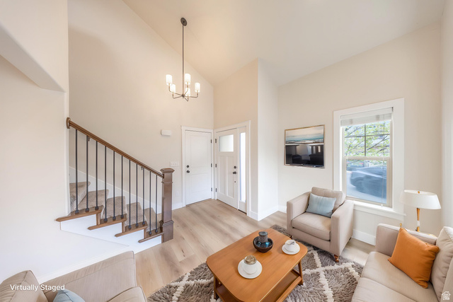 2169 Orchard Pines Loop East Bountiful, UT 84010 - Photo 8 of 32 Foyer and living area featuring high ceilings, wood-finish flooring, a contemporary chandelier, a white paneled front door with sidelight, and a staircase with wood newel posts and iron balusters